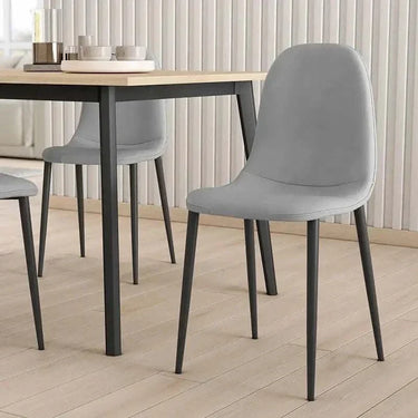 Silla de comedor gris en microfibra suave, con asiento curvo sin reposabrazos y patas metálicas negras.