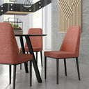 Silla de comedor tapizada en tejido salmón, con respaldo alto y patas metálicas negras de líneas rectas.