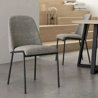Silla de comedor tapizada en gris jaspeado, con asiento y respaldo mullidos y patas metálicas negras.